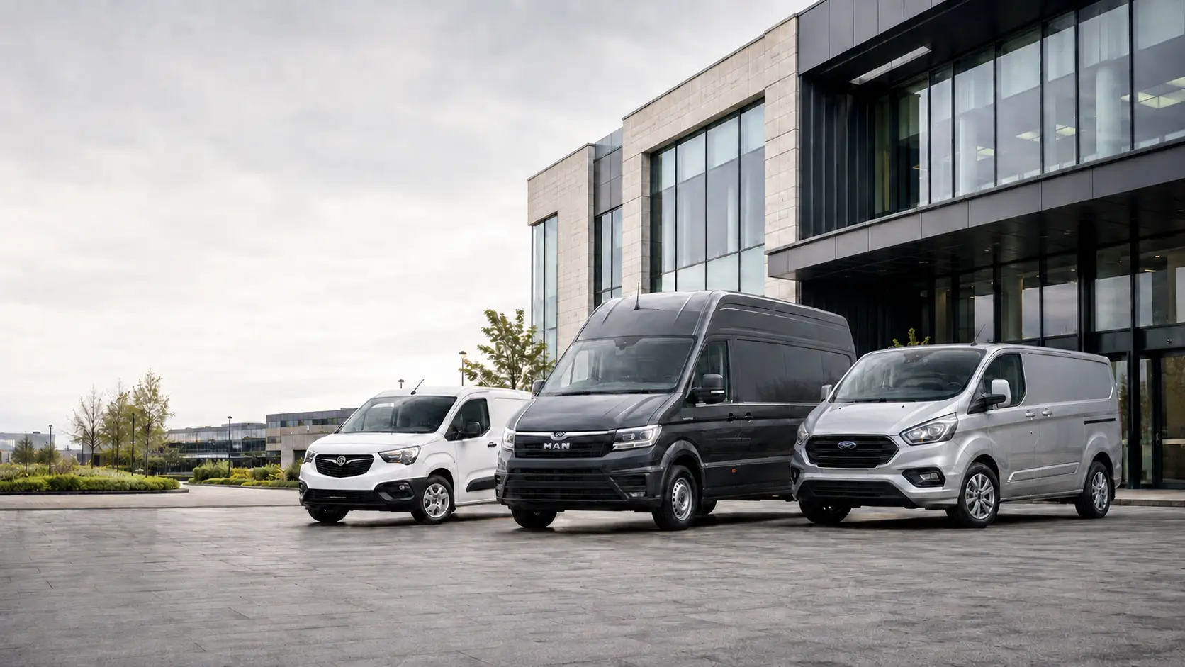 Three commercial vans outside a modern business building